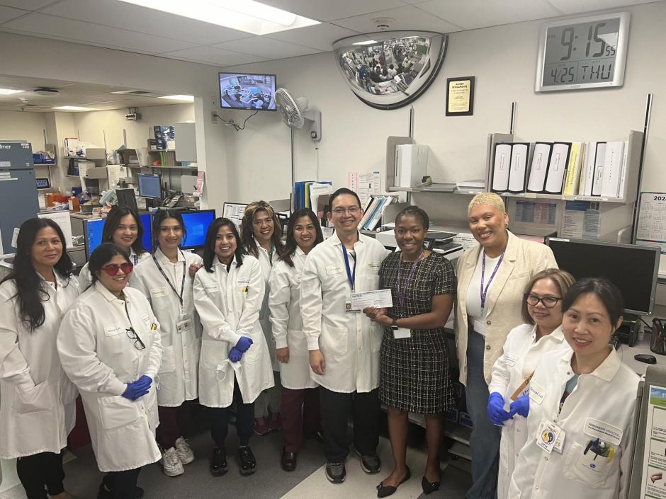 Employees from the Kaiser Permanente Morse Avenue Laboratory Department and WEAVE Director of Philanthropy & Communications Shanté Johnson in the lab holding check for  $1,150 for WEAVE.